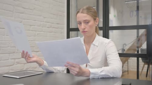 Mature Business Woman Reading Documents at Work