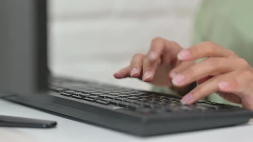 Nahaufnahme einer weiblichen Hand, die auf der Computertastatur tippt
