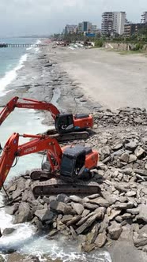 Vertical Video Reshaping Nature's Canvas Aerial View of Heavy Machinery on the Stone Beach