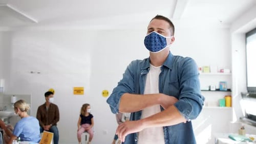 People Wearing Face Masks Waiting in Vaccination Room