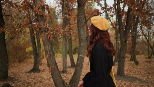 Stylish Lady Strolling Through Autumn Forest in Yellow Beret and Black Coat
