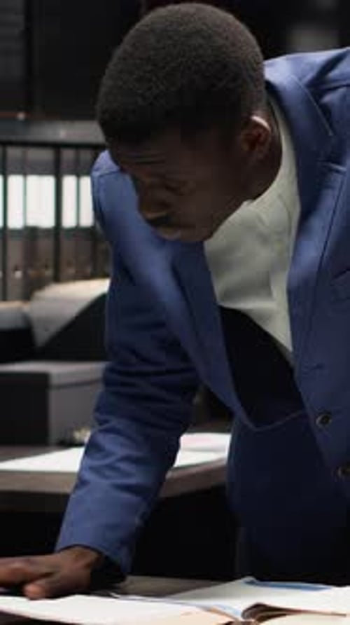 Concerned Man in Suit Reviews Documents at Desk