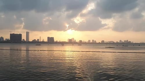 an astonishing view of the sunset and the drifting clouds above the water with the city on the backg