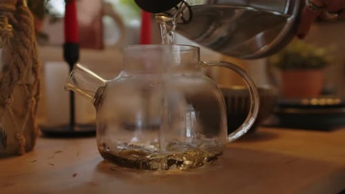 Pouring Water into Glass Teapot to Brew Tea