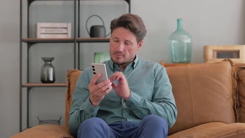 Man Using Smartphone While Sitting on Couch