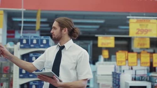 Handsome Man the Seller Work Use Tablet Computer Walk in Tech Department in Supermarket Feel Happy