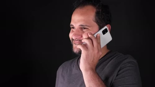 Man Talking on Phone in Front of Black Backdrop