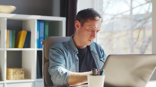 Young Male Entrepreneur Works at Home Office at the Computer Workplace of Freelancer or Student