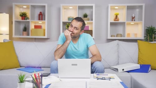 Home office worker man biting his nails looking at camera.