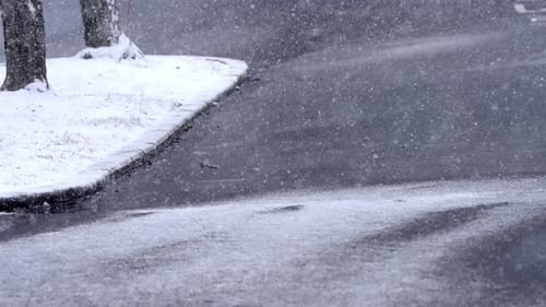 Schneefall in Zeitlupe auf einer Straße, Straße, Asphalt an einem Wintermorgen, Schneeflocken fallen bei kaltem Wetter