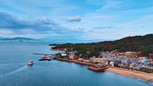 Flying closer to the shore of Japan Inland Sea built by multiple houses and covered