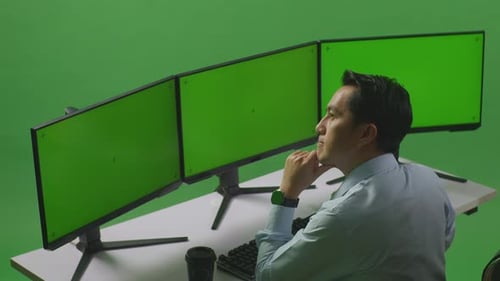 Asian Man Thinking While Working With Mock Up Multiple Computer Monitor In Green Screen