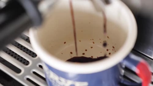 Slow motion close up of espresso maker dripping coffee into blue coffee mug
