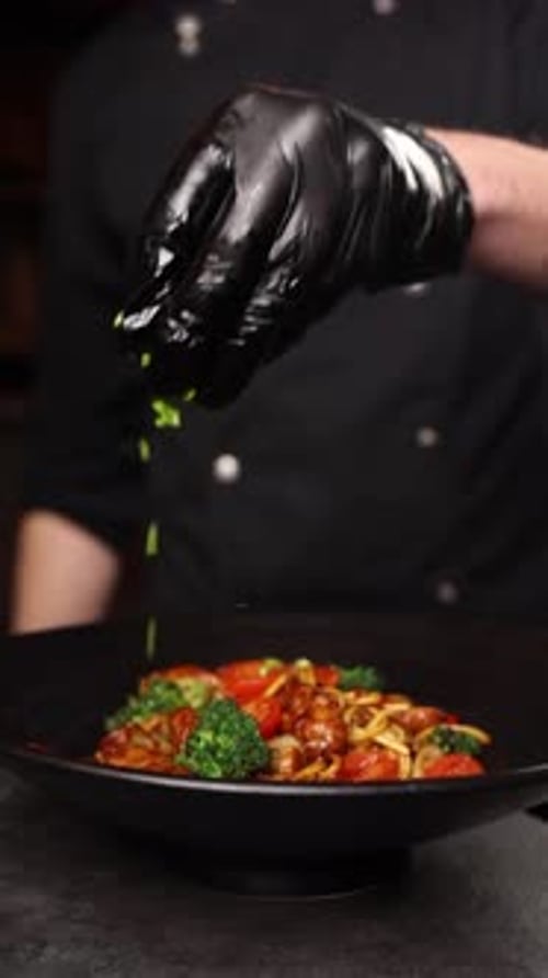 Chef Garnishing Noodle Dish with Fresh Herbs