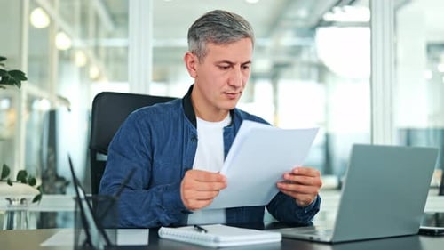 Focused Businessman Reviewing Documents in a Modern Office