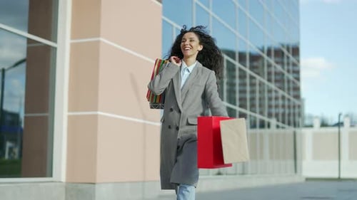 Smiling Woman with Shopping Bags Walks in City