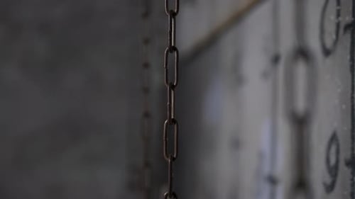 Chains Hanging Near a Gray Wall with Various Numbers in a Dark Scary Room