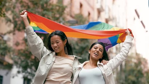 Two Women Celebrate Pride with Rainbow Flag on Street