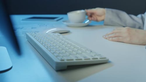 Woman Typing on Keyboard and Drinking Coffee
