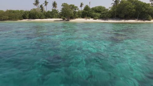 Drone flying up and over a tropical island in the maldives
