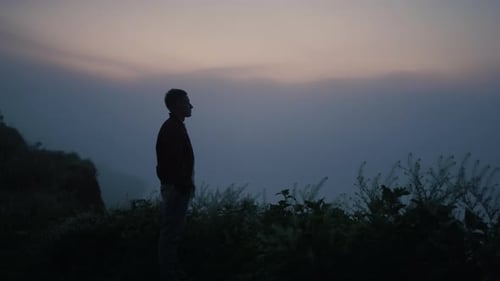 Traurige Männer-Silhouette, die morgens auf einem Berggipfel steht. Einsamer Kerl sucht