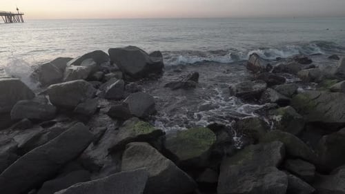4k Little waves crashing on rocks at the beach in the mediterranean sea on a warm beautiful morning