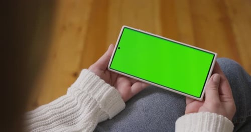 Woman Hands Holding Smartphone with Green Screen in Horizontal Position