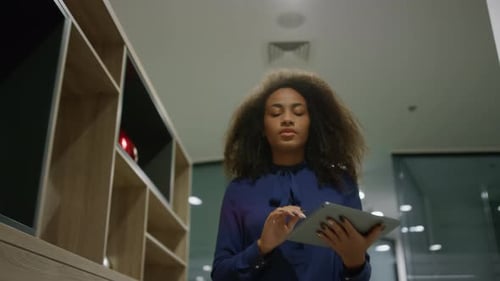 African american businesswoman browsing internet on tablet in modern office hallway