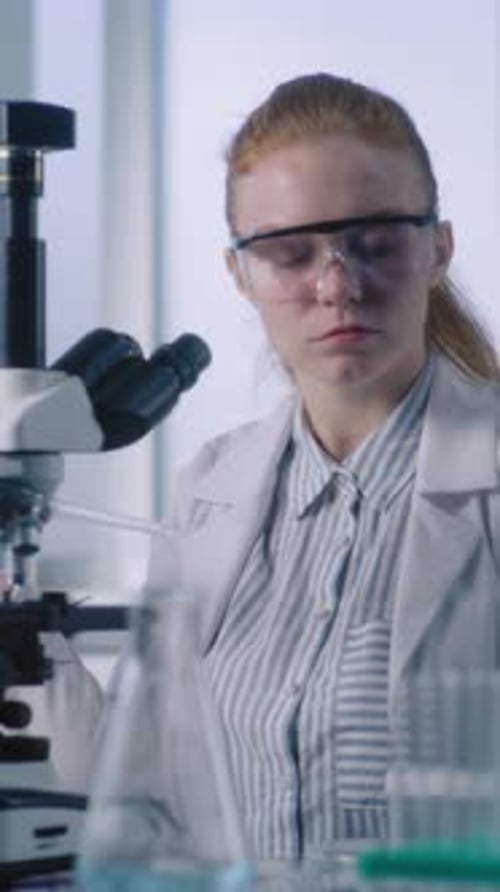 Female Scientist Works with Microscope in a Laboratory