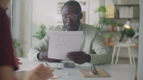 Black Businessman Discussing Papers with Colleague in Office