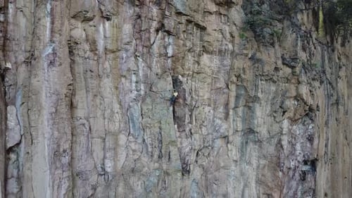 Rock Climber Ascends a Jagged Cliff Face
