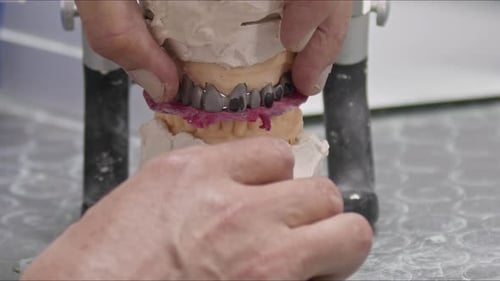 Dental Technician Adjusting Teeth on a Dental Model