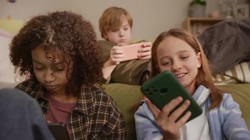 Children Using Smartphones Sitting on Couch Indoors