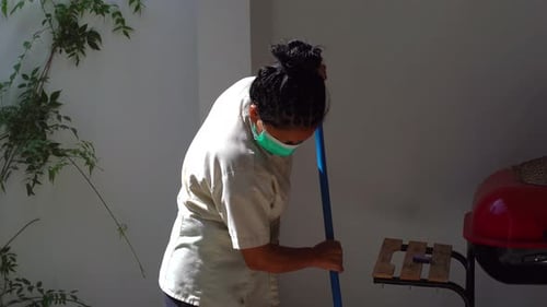 Woman Sweeping Patio in the Daytime