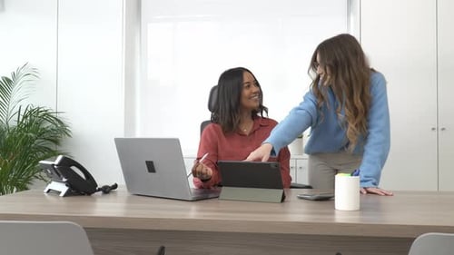 Businesswomen Collaborating on Tablet in Modern Office