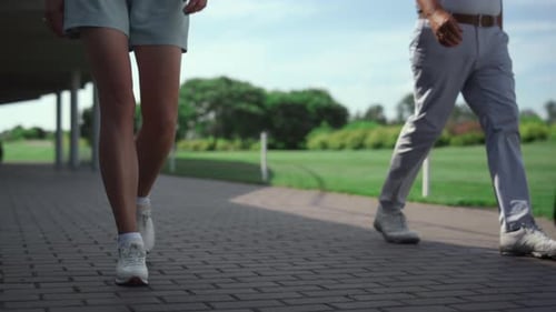 Golf Professionals Walk Together at Grass Course. Couple Legs Going on Golfing