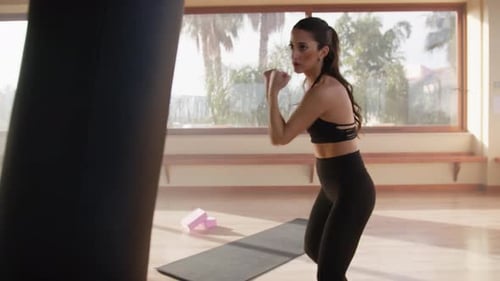 Woman Punches and Kicks Punching Bag in Gym