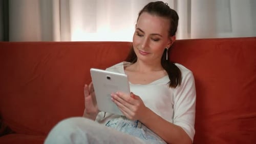 Woman Using Tablet Device on a Couch Indoors