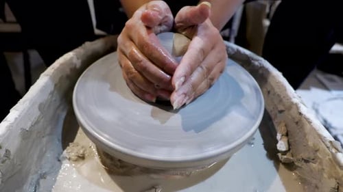 overhead close view of an African American hands spinning clay very sporadically while pushing the m