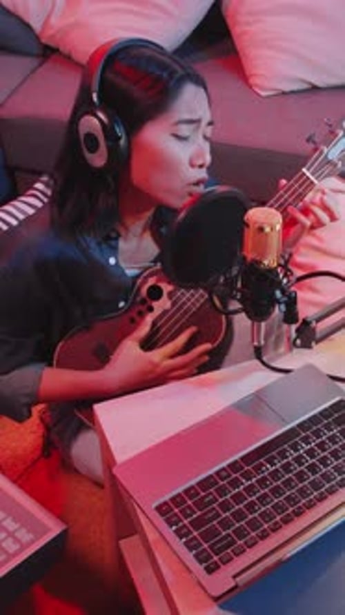 Asian Female Musician Singing to Ukulele Music while Recording Song at Home