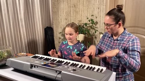 Child Learning Piano with Teacher Indoors