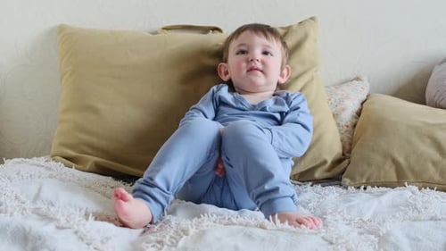 Child Relaxing on Bed Wearing Blue Pajamas