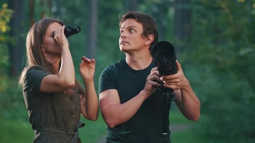 Birdwatching in park. Couple watch birds with binoculars and camera with telephoto lens