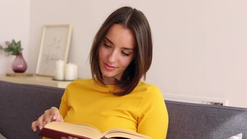 Woman Reading a Book on Couch at Home