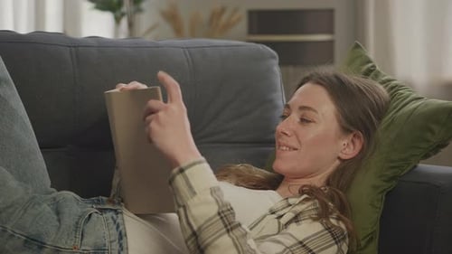 Woman Reads Book on Couch Indoors