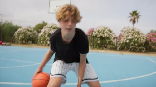 Teen Practices Basketball on Outdoor Blue Court