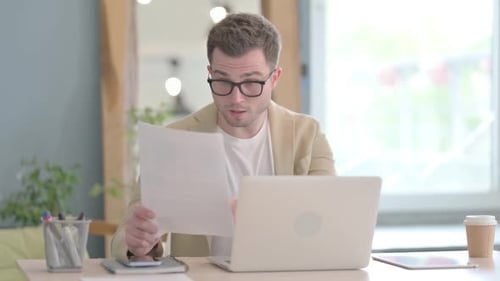 Man Reads Document and Celebrates Achievement