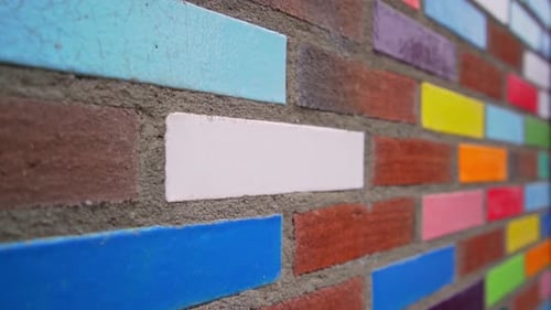 Colourful decorative bricks laid in a red brick outside wall of a building