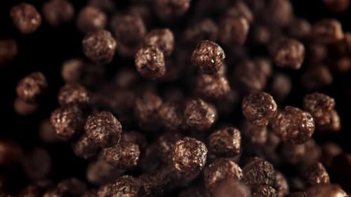 Chocolate Cereal Puffs Floating on a Black Background