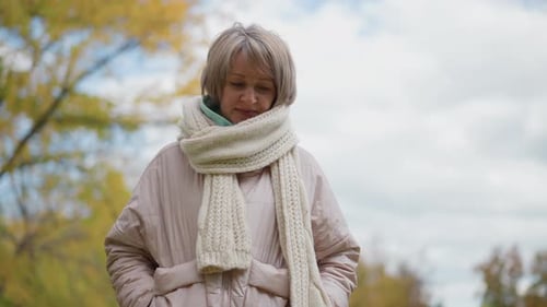 Woman Adjusting Neck Scarf in Autumn Garden